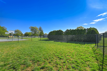 Fenced sports field with basketball court and green space